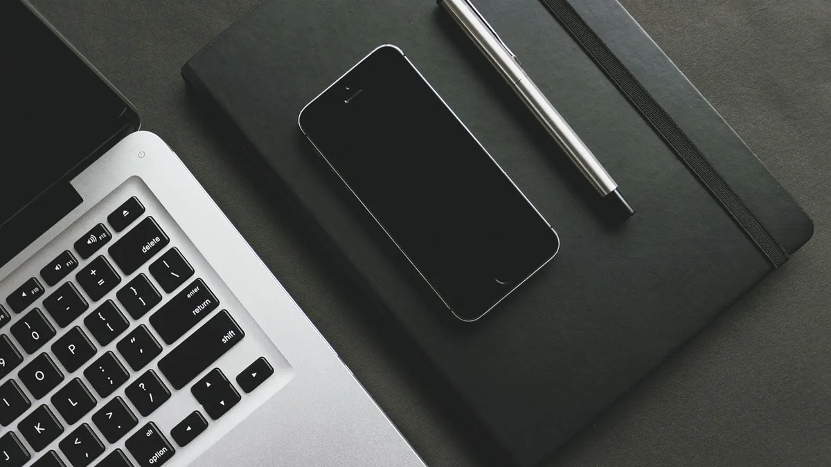 Dizüstü bilgisayar, telefon, kalem ve kapalı not defteri