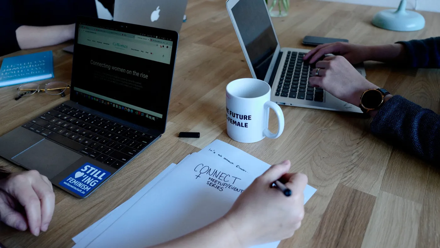Masada iki dizüstü bilgisayar ve elle not alınan bir defter