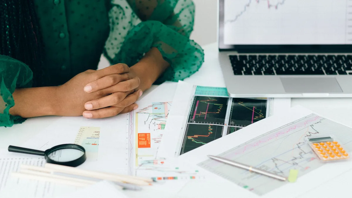 Grafik baskıları ve bilgisayar yanında notları inceleyen kişi