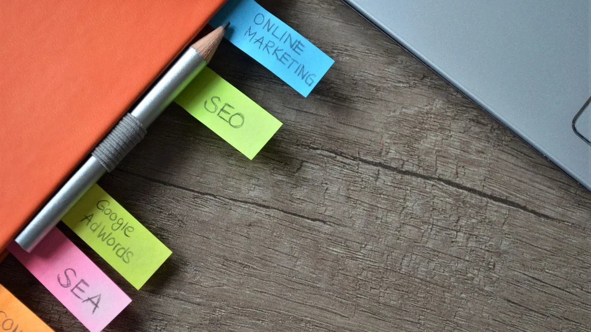 SEO etiketli renkli not kâğıtları, kalem ve kapalı dizüstü bilgisayar