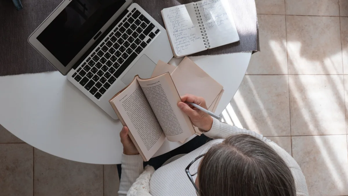 Masa başında kitap ve notları inceleyen kişi