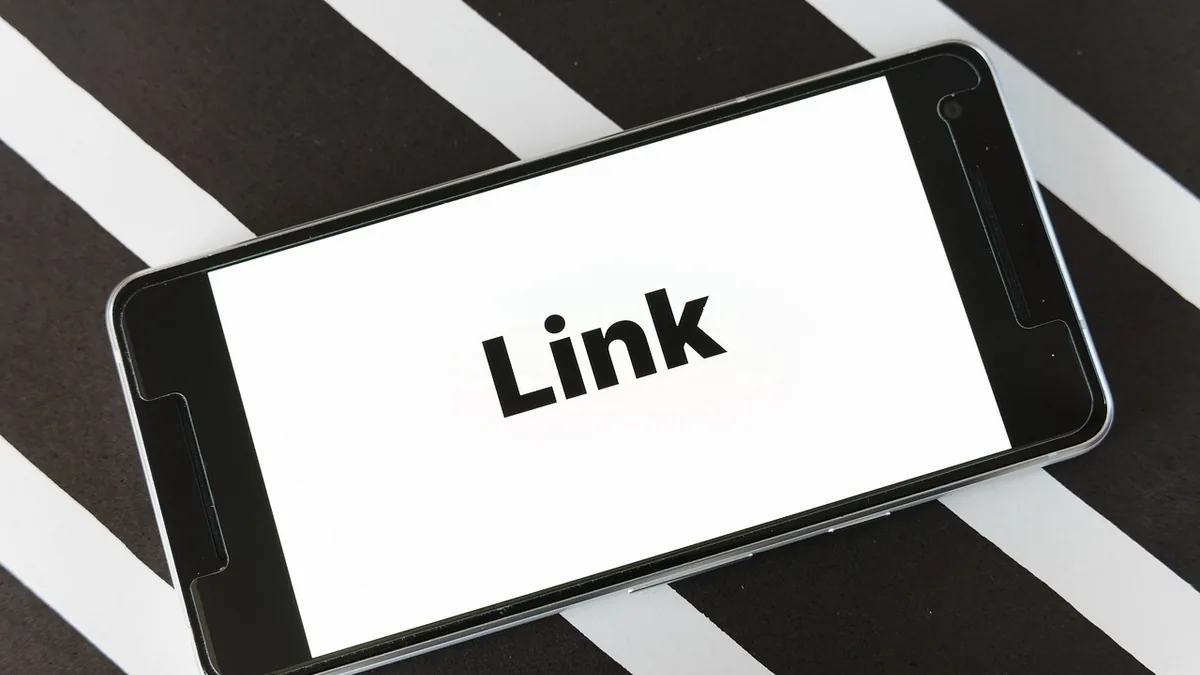 Ekranında Link yazan telefonun masa üzerindeki görünümü
