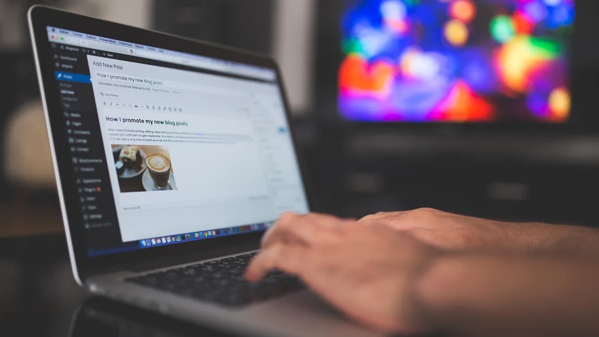Web sitesi yönetim ekranı açık dizüstü bilgisayarda yazı yazan kişi