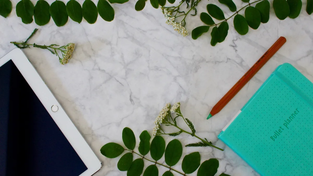 Ekran, tablet, defter ve bitkilerin bulunduğu çalışma masası