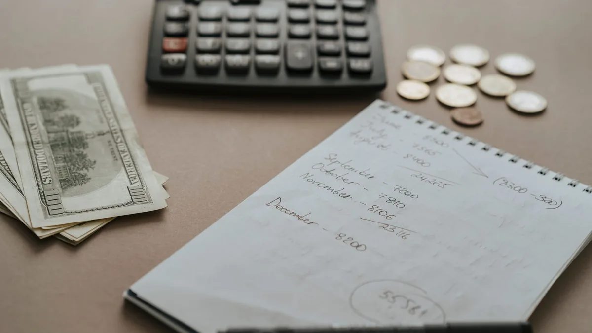 Hesap makinesi, banknotlar ve bütçe notlarının bulunduğu masa
