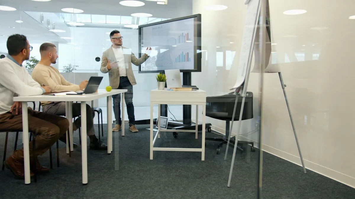 Sunum ekranının önünde iş planını değerlendiren ofis ekibi