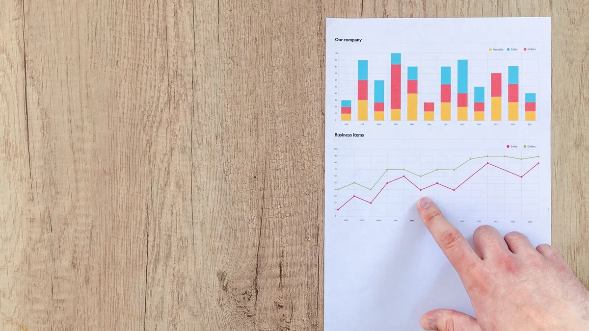 Basılı grafik sayfasındaki çizgiyi parmağıyla inceleyen kişi