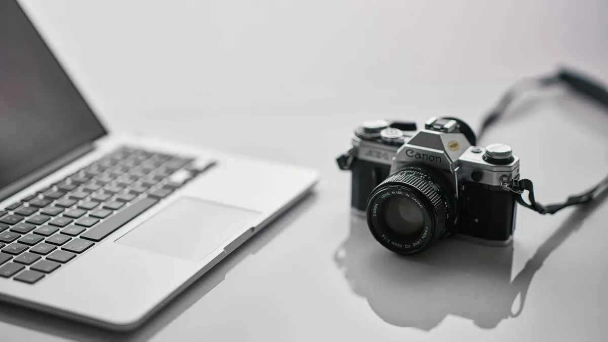 Dizüstü bilgisayar yanında fotoğraf makinesi ve çalışma araçları