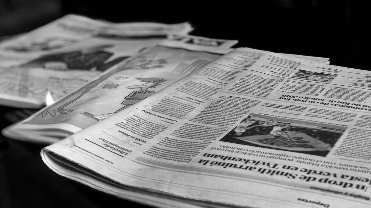 Ahşap masa üzerinde farklı gazetelerin sayfaları