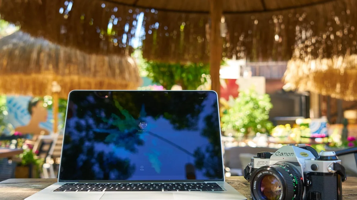 Dizüstü bilgisayar yanında fotoğraf makinesi ve çalışma araçları
