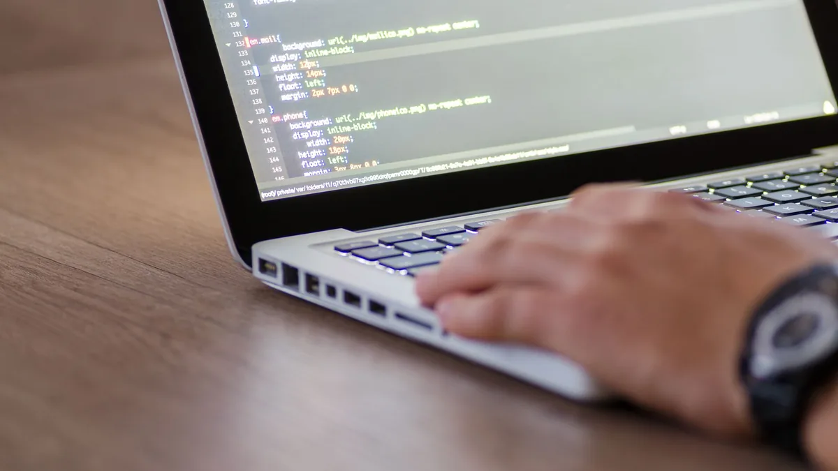 Ekranında HTML kodu açık dizüstü bilgisayarda çalışan kişi