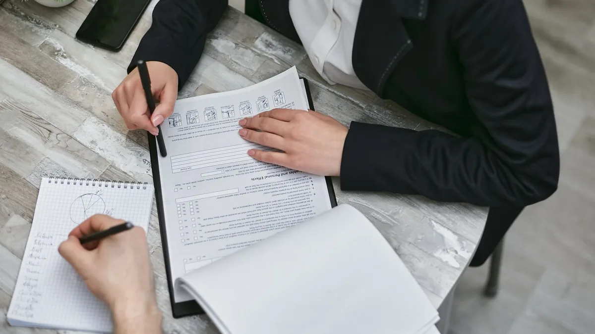 Ofis masasında belgeleri birlikte inceleyip not alan iki kişi