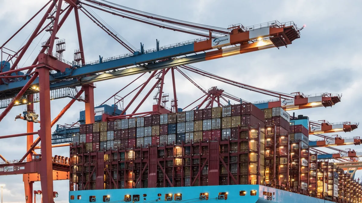 Hamburg limanında vinçlerin yanında konteyner yüklü kargo gemisi