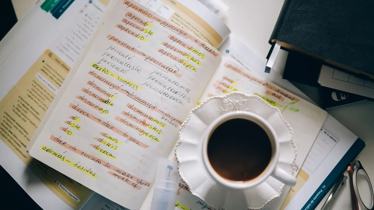 Yabancı dil notları yazılı defter ve yanında kahve fincanı