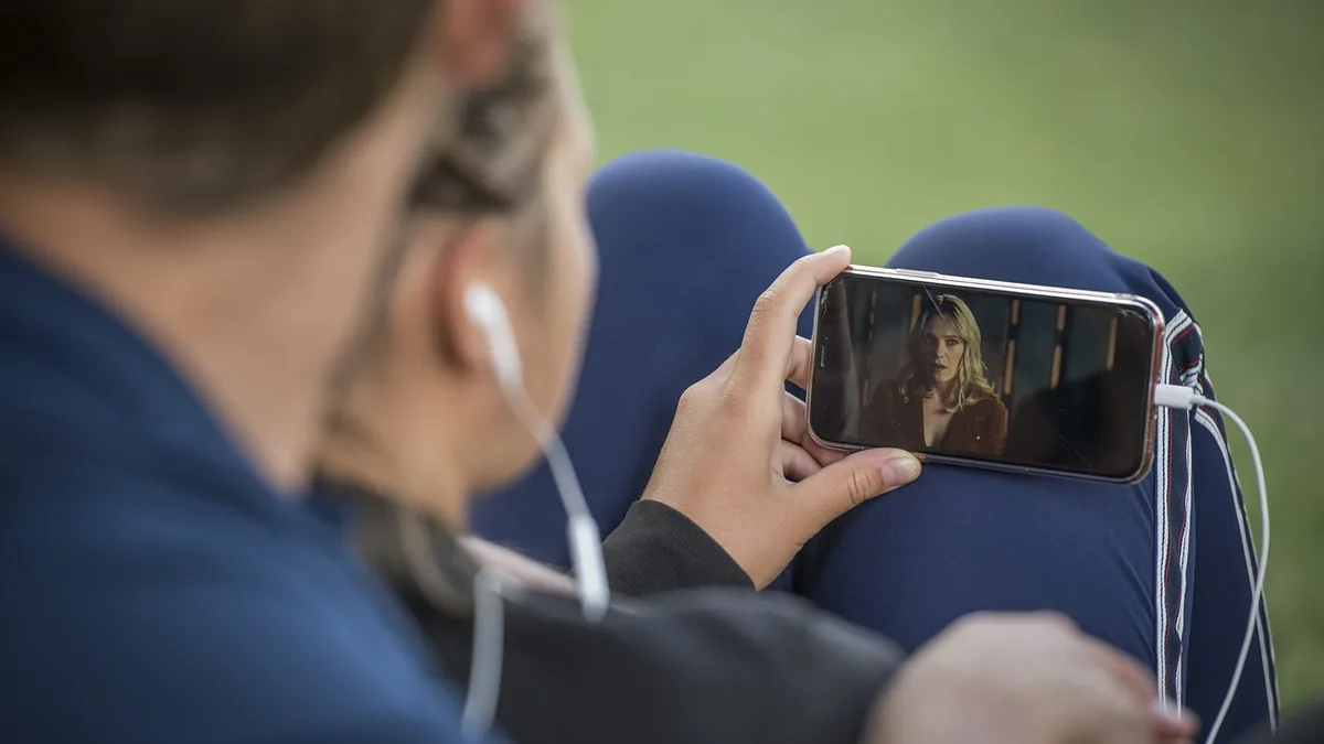 Parkta telefon ekranındaki videoyu birlikte izleyen iki kişi