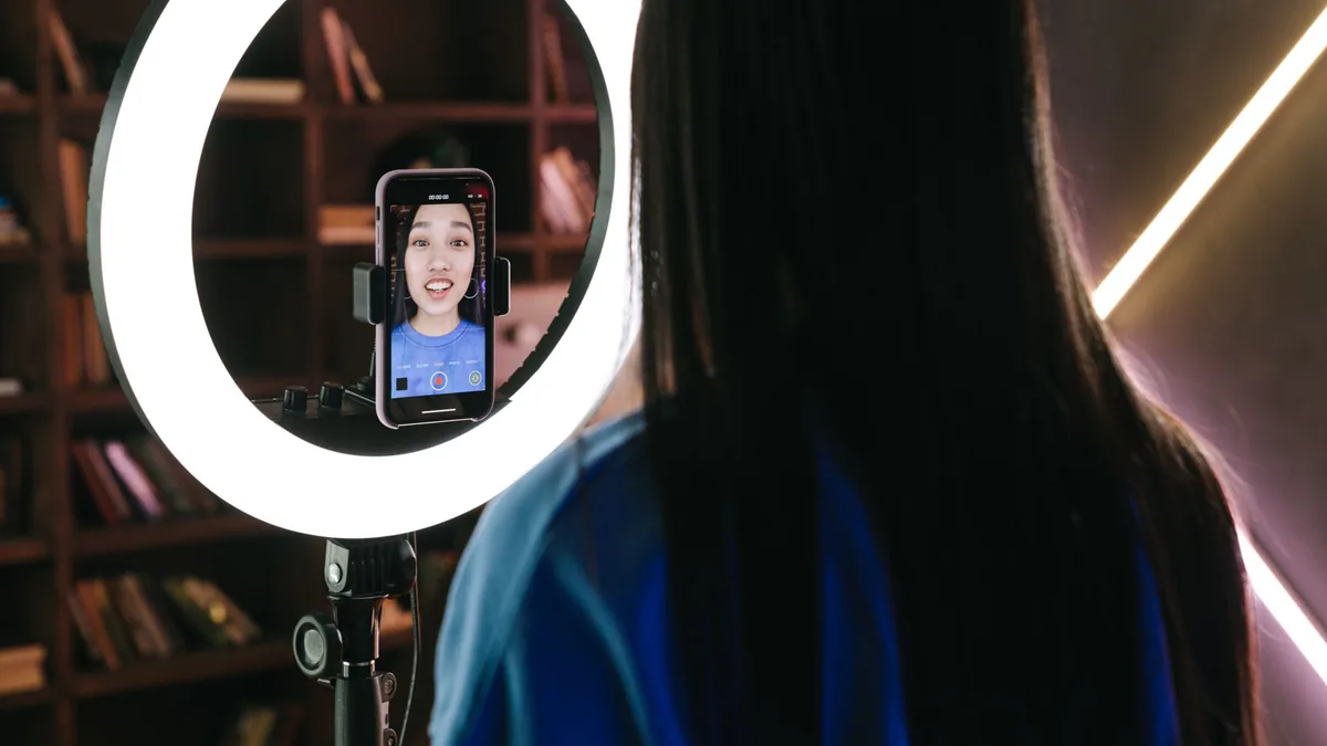 Halka ışık önünde telefonla dikey video kaydeden içerik üreticisi