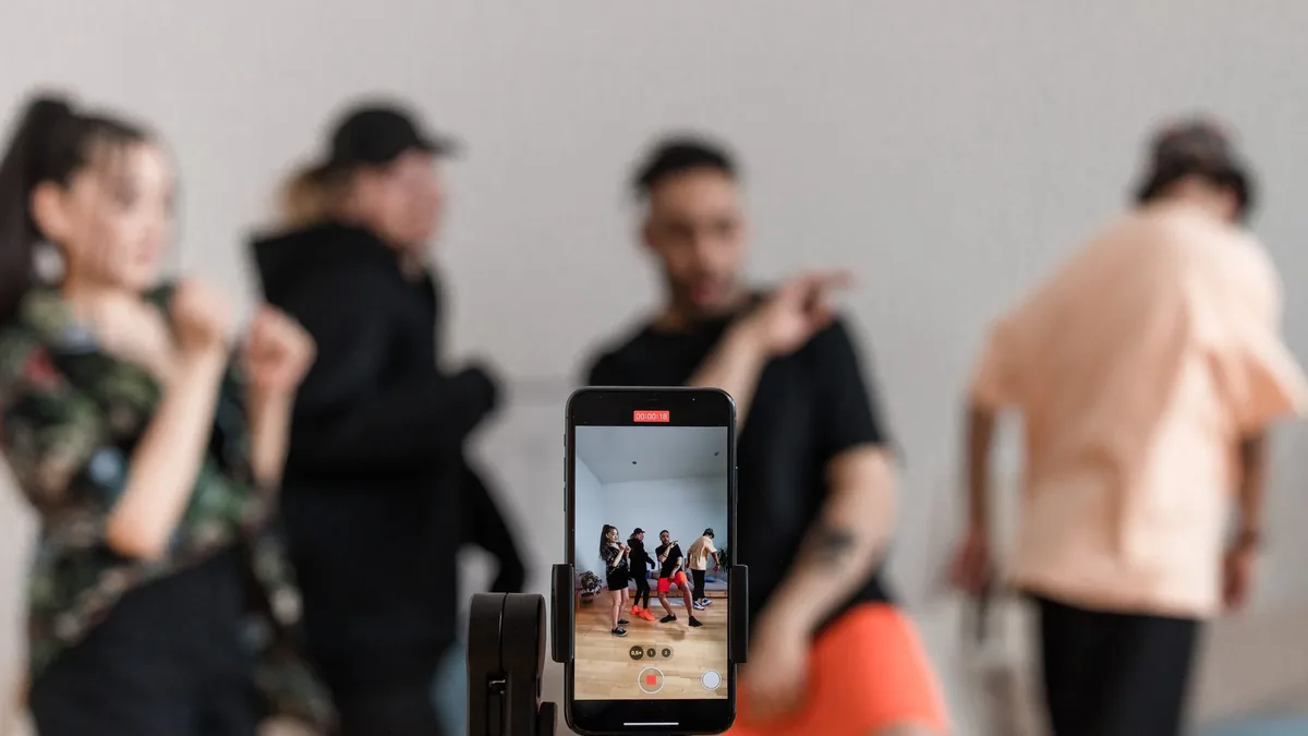 Telefon kamerası önünde video içeriği hazırlayan kişiler