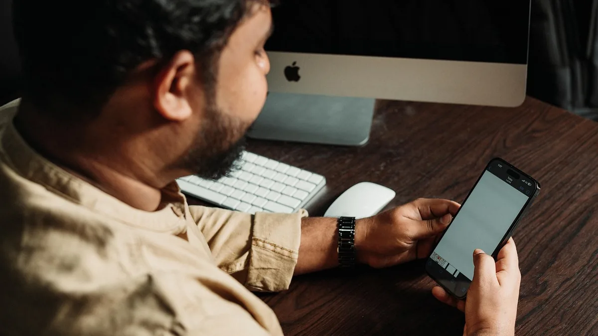 Sosyal medya simgelerinin yanında telefon kullanan kişi