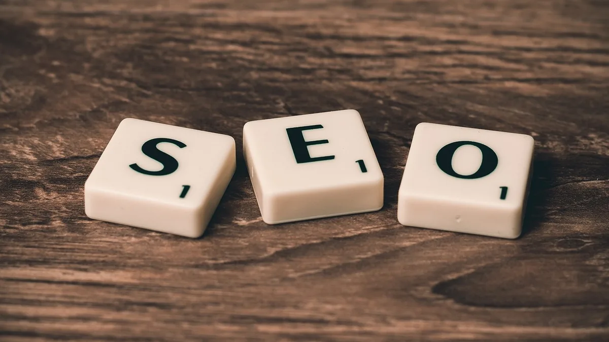 Ahşap yüzeyde SEO harflerini oluşturan üç açık renkli taş