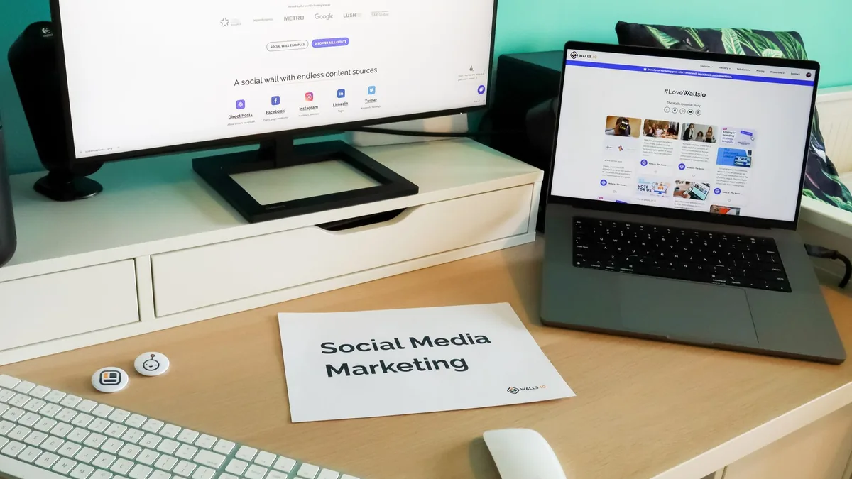 Sosyal medya akışlarının açık olduğu monitör ve dizüstü bilgisayar bulunan çalışma masası
