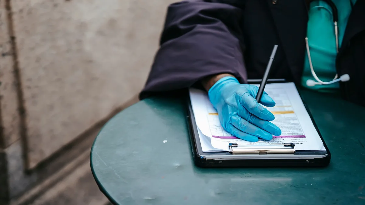 Stetoskoplu sağlık çalışanının tablet üzerindeki belgeye not alması