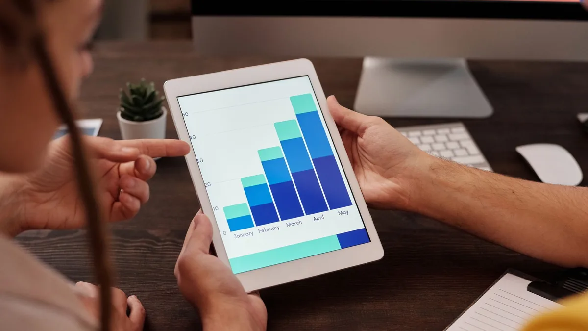 Toplantı masasında tablet üzerindeki grafiği inceleyen kişiler