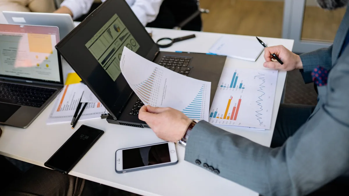 Toplantıda basılı raporu elinde tutan kişi ve çalışma masası