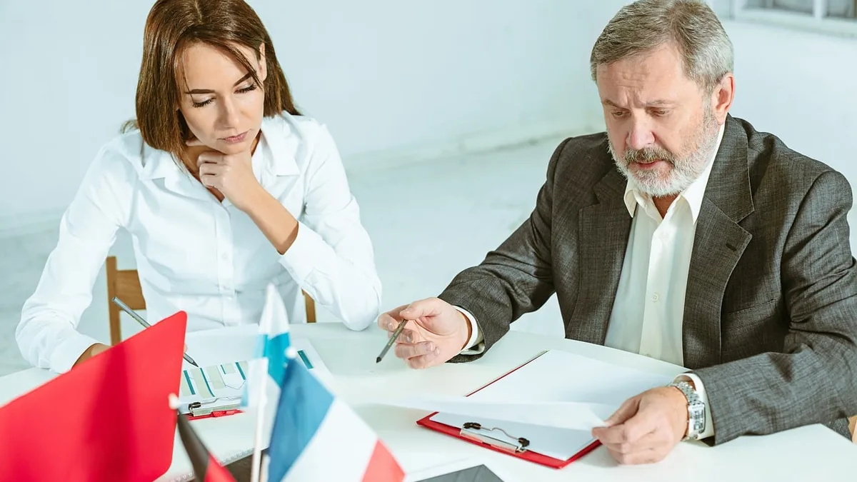 Ofis masasında belge üzerinden görüşen iki kişi