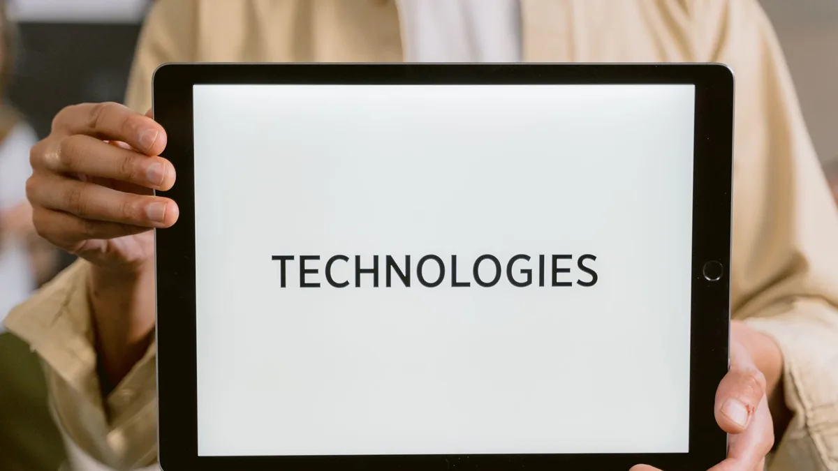 Ekranında Technologies yazan tableti iki eliyle tutan kişi