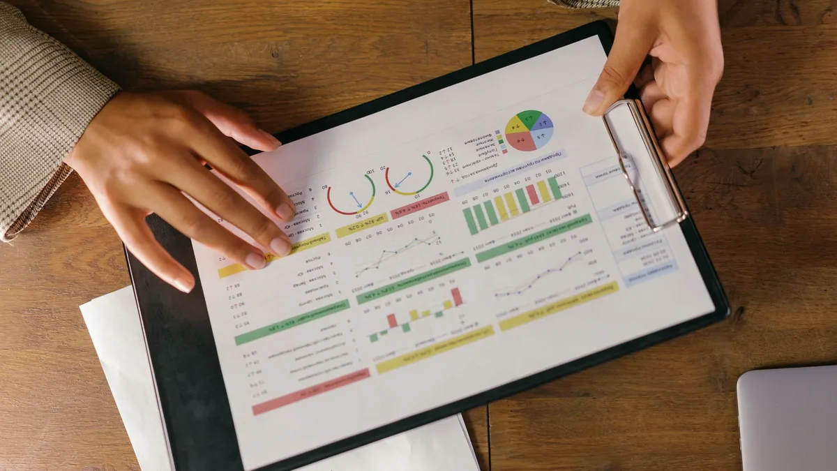Ellerinde grafik bulunan rapor panosunu inceleyen kişiler