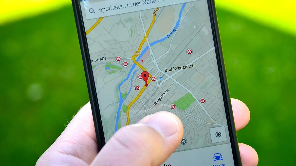 Harita ve konum işaretleri açık olan cep telefonunu tutan el