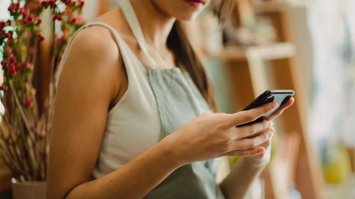 Bir mağazanın içinde cep telefonunu kullanan işletme çalışanı