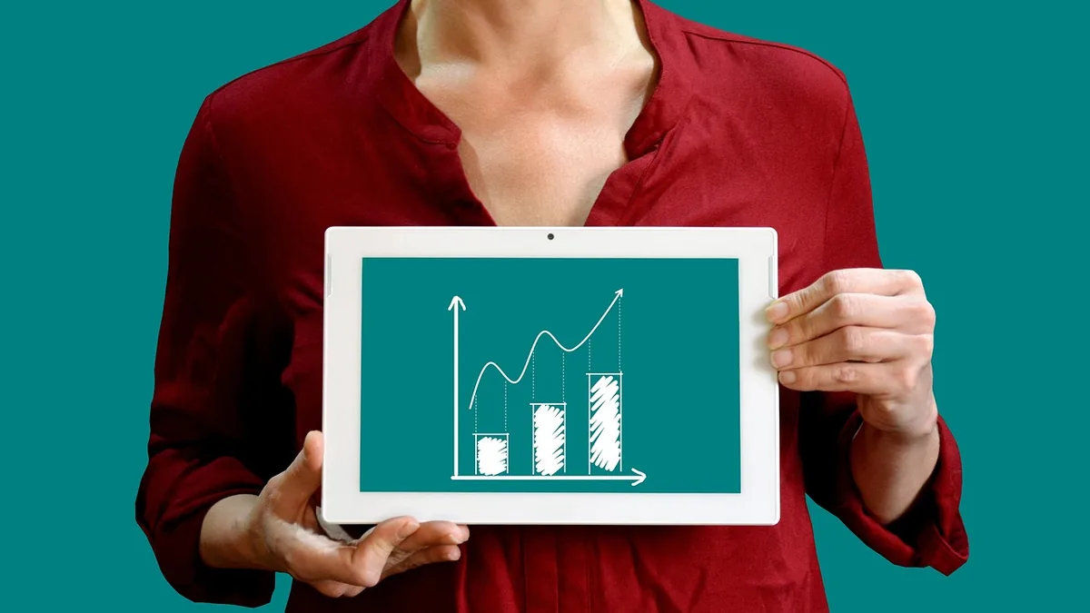 Elindeki tablette yükselen grafik gösteren kırmızı gömlekli kişi